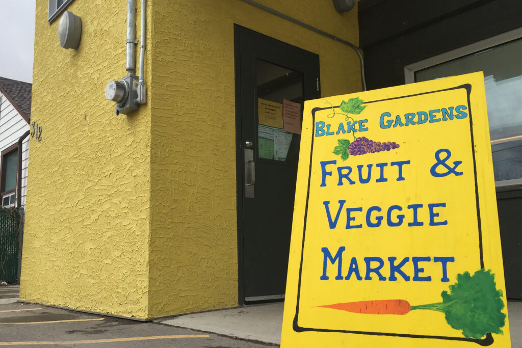 A yellow sign for Blake Gardens' fruit & veggie market sits outside the agency.