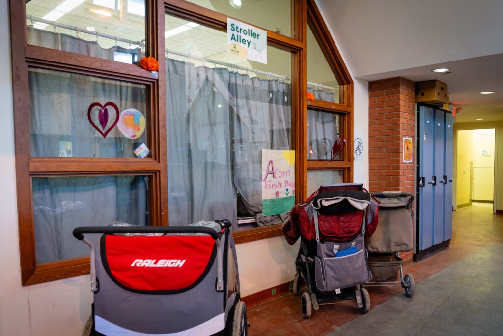 Three strollers are parked outside of the licensed nursery beneath a sign that reads "Stroller Alley."